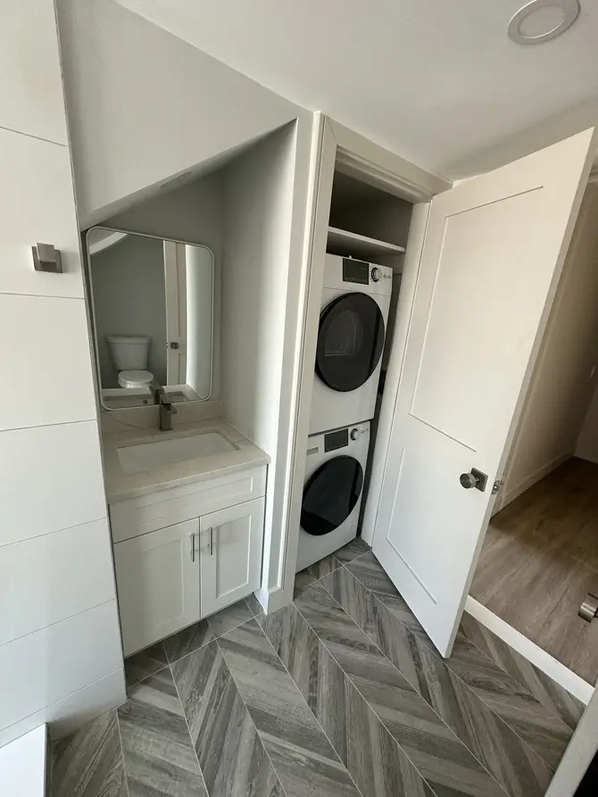 Laundry area with built-in storage and stacked washer and dryer