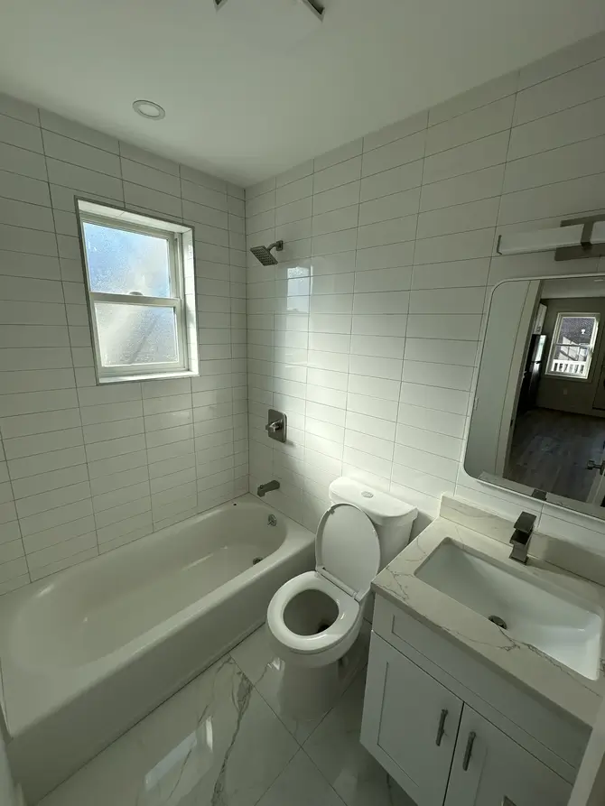 Bathroom with bathtub, vanity and tiled walls